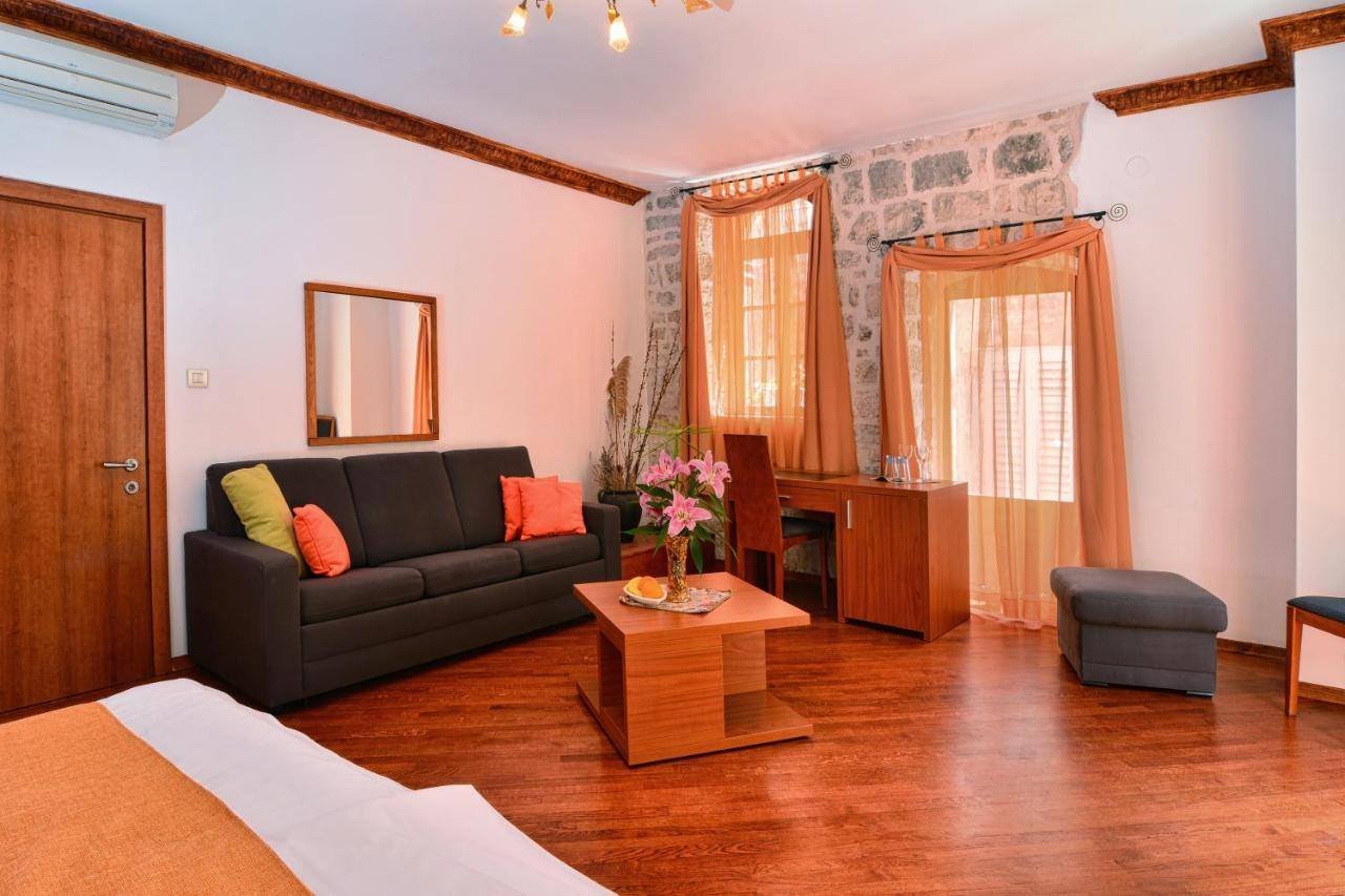 Villa Nora Hvar: room with an orange sofa, a desk and old stone walls