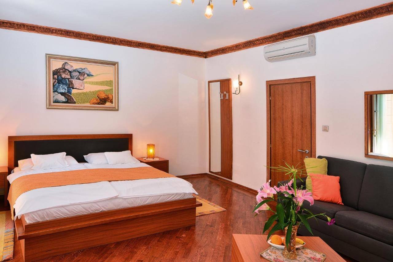 Villa Nora Hvar: double room with a wooden bed, a sofa and a painting