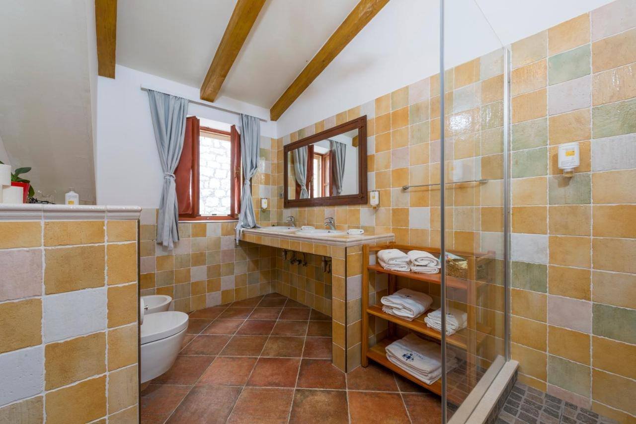 Villa Nora Hvar: bathroom with ochre tiles, double sink and a glass shower