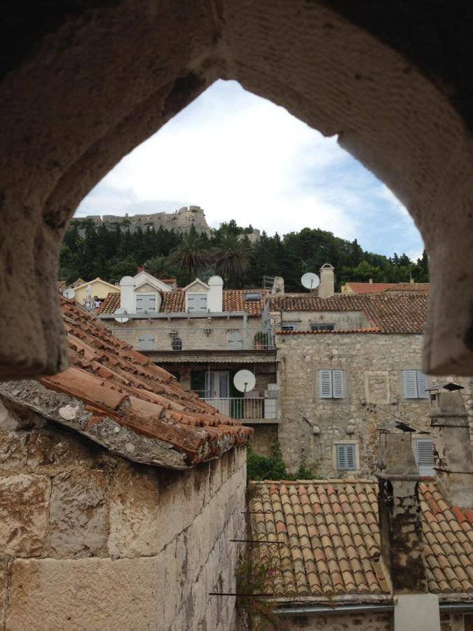 View of the old town rooftops and the fortress through a stone arch